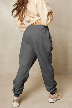 Person wearing gray sweatpants and a beige top on a beige background