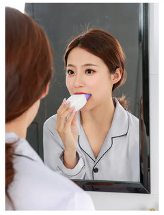 Woman using a  Ultrasonic Automatic Mouth with Toothbrush! In white in front of a mirror