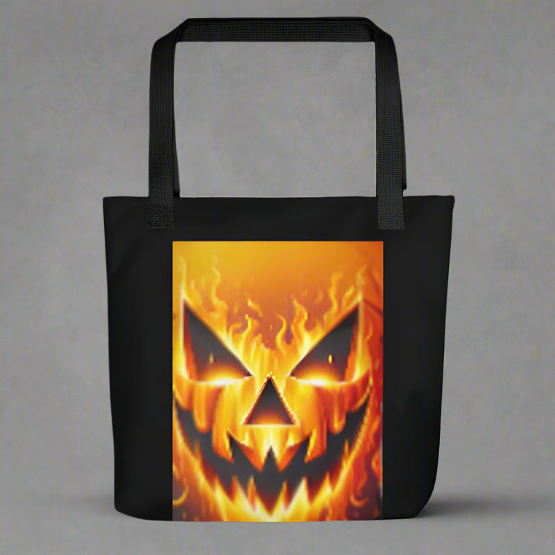 Black tote bag with a fiery pumpkin face design on a white background