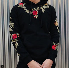 Black hoodie with floral embroidery on a striped background