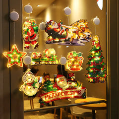 Decorative Christmas lighted ornaments  with Santa Claus, reindeer, and other festive elements hanging on a glass door.