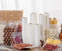 Plastic wrap rolls with various food items on a white background