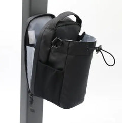 Black backpack with multiple pockets attached to a pole on a white background
