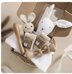 Baby care items including a plush bunny, wooden brush, and rattle in a basket.