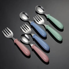 Set of colorful children's cutlery including spoons and forks on a dark background