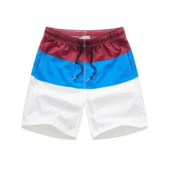Color-blocked beach shorts with red, blue, and white sections on a white background