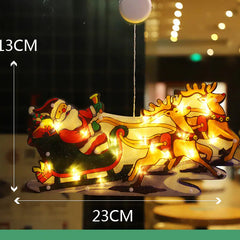 Decorative Christmas sleigh with Santa Claus and reindeer, illuminated by string lights, on a blurred indoor background.