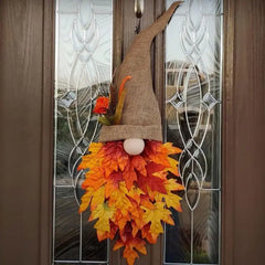 Decorative autumn-themed gnome with leaf skirt hanging on a door.