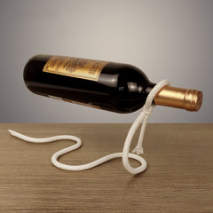 Wine bottle tied with a rope that looks like suspended in mid air, but the rope is actually a wrought iron stand balanced to hold the bottle.