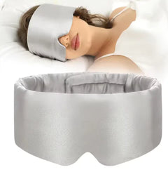 Woman wearing a gray silk sleep mask with a matching headband on a white background