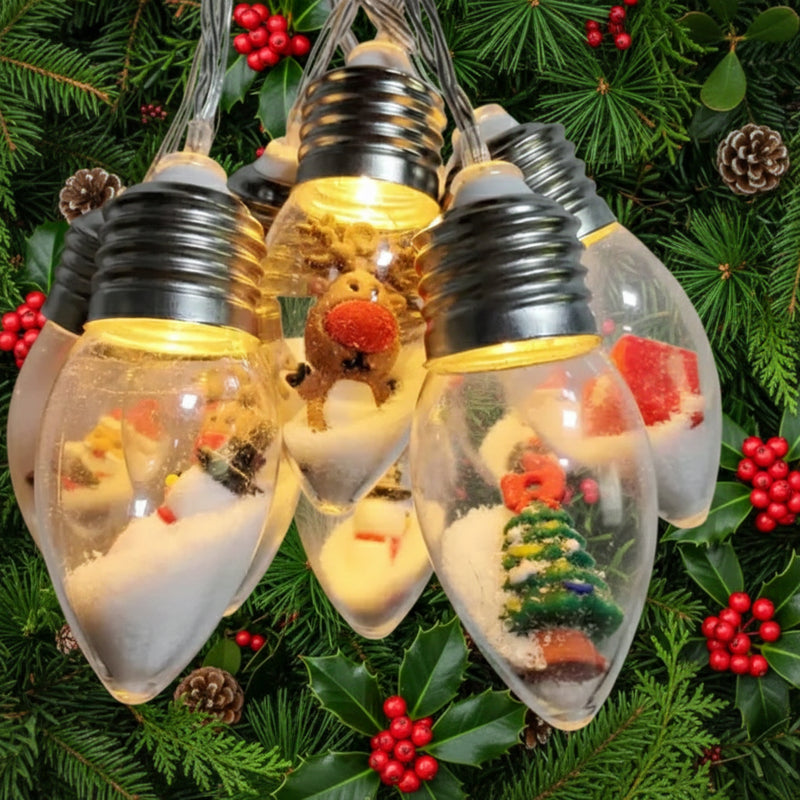 String lights with decorative bulbs featuring small scenes inside with a backdrop of Christmas greenery